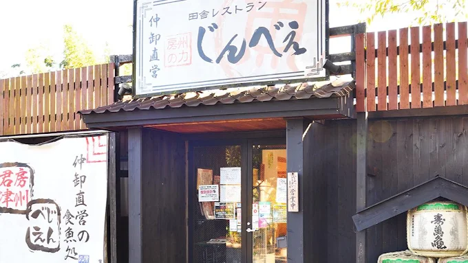 木の塀と看板が目を引く田舎レストランじんべえの店舗外観