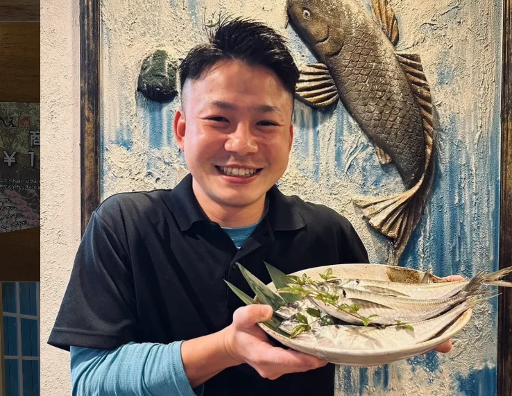新鮮な魚を盛り付けた皿を持って笑顔を見せるスタッフ