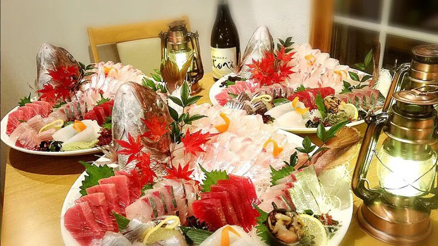 ランタンの灯る食卓に並ぶ、鯛の頭付きの刺身盛り合わせ