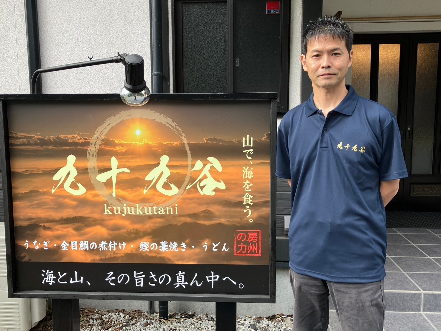 九十九谷の看板の前に立つスタッフ